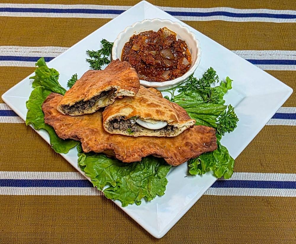Golden patté filled with spiced beef and boiled egg, served on lettuce with a bowl of onion sauce